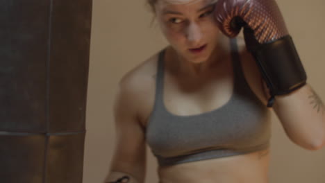 Medium-shot-of-woman-in-boxing-gloves-hitting-punching-bag